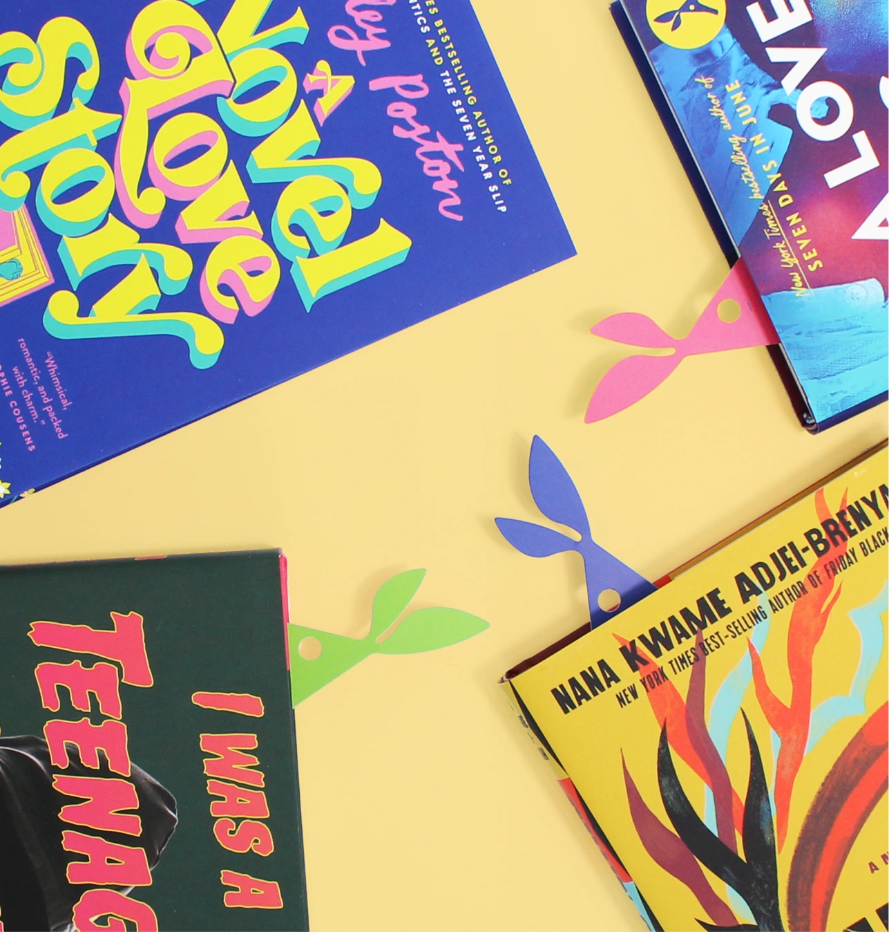 Four colorful books arranged on yellow background with bunny-ear shaped paper bookmarks.