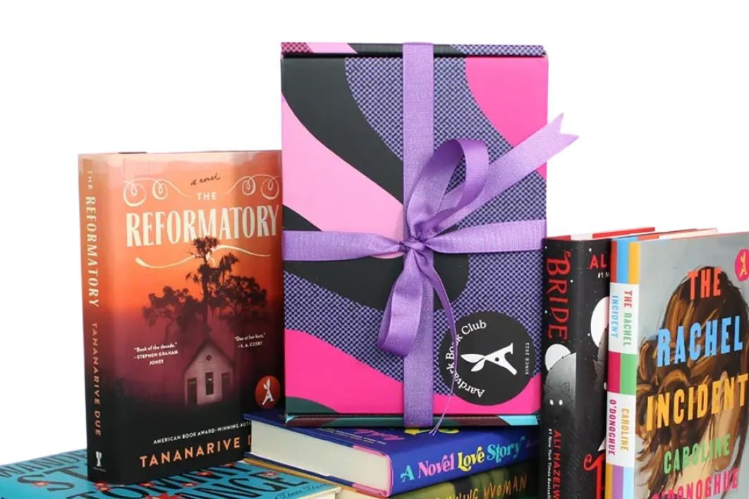 Stack of colorful books with a pink and purple gift box tied with a purple ribbon on top.